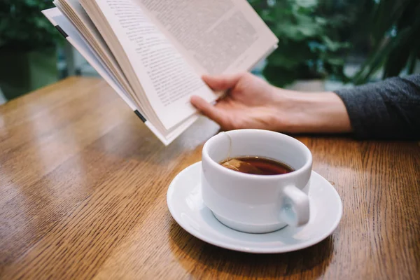 Herbata na stole, a książkę w ręce ludzi — Zdjęcie stockowe