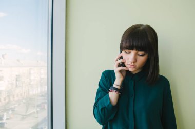 Genç güzel kadın memur aşağı pencere ve görünüyor telefonda konuşurken