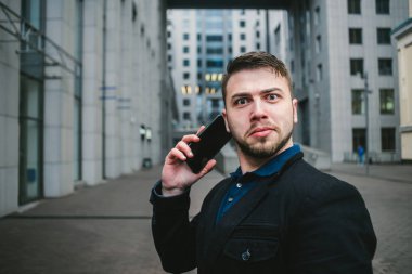 Komik şaşırmış adam ve modern kentsel peyzaj arka telefonda konuşurken işadamı. İş kavramı