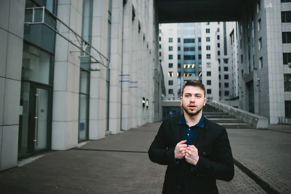 Retrato ao ar livre de um jovem empresário sério com barba no pano de fundo da bela arquitetura moderna . — Fotografia de Stock