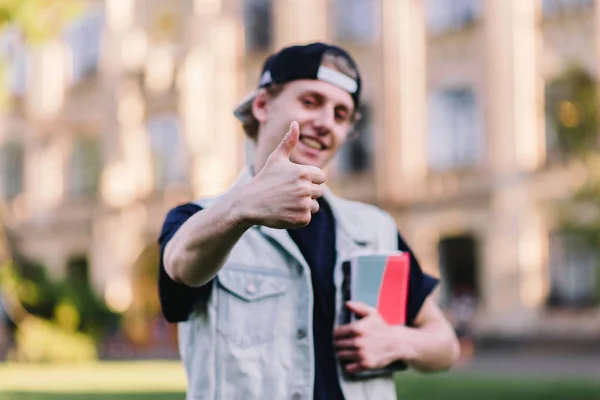 Student hält Buch in der Hand und zeigt Daumen hoch — Stockfoto