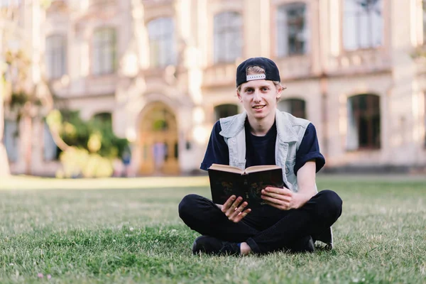 Joven estudiante leyendo libro en el campus — Foto de Stock