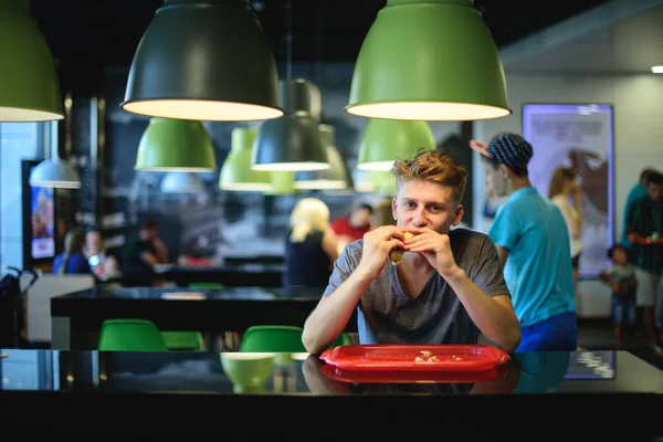 학생 탐욕 좋은 아름 다운 햄버거 패스트 푸드 레스토랑에 앉아 먹는. — 스톡 사진