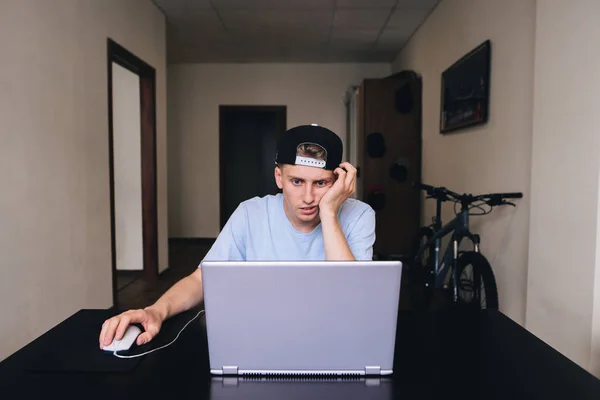 A tired student stares at the notebook monitor in the room of his home. Teen room — Stock Photo, Image