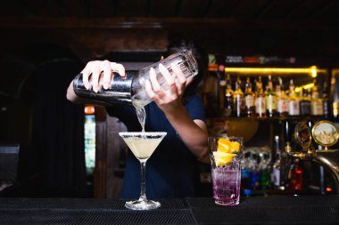 Barmen güzel alkollü kokteyl barda oluşturur. Barmen shaker malzemelerle dışarı dökülen.