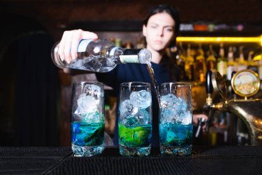 Bir kız barmen restoranda güzel bir alkollü kokteyl yapar. Barmen şişe alkol dökülen.