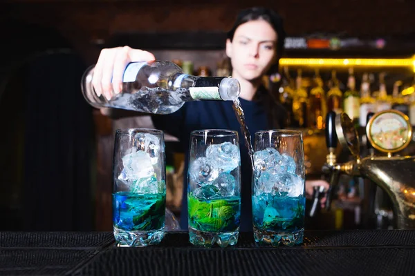 Дівчина бармен робить красивий алкогольний коктейль в ресторані. Бармен п'є алкоголь з пляшки . — стокове фото