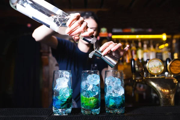 Bartender mencampur bahan-bahan koktail biru yang indah. Bartender menuangkan alkohol ke dalam koktail. Minuman beralkohol di bar. — Stok Foto