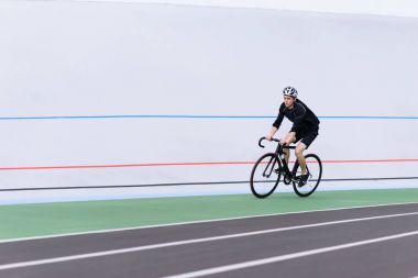 Açık bir profesyonel yolda siyah giysili bir bisikletçi eğitim. Spor.