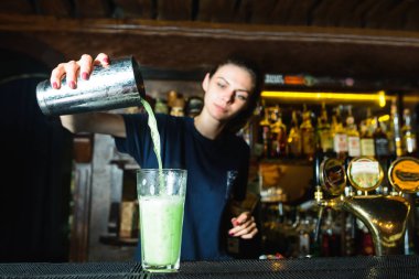 Barmen bir kokteyl barda Pastalar. Bir barmen kız bir shaker madde bir kokteyl bardağına dökülen..