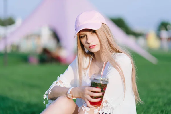 Retrato de uma menina bonita elegante que tem um descanso no parque e bebe uma bebida fresca. Férias — Fotografia de Stock