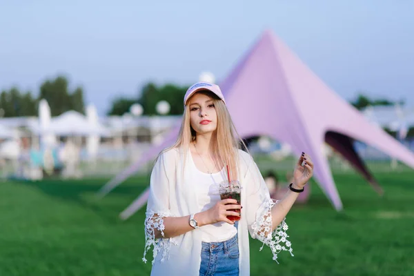 Jovem menina bonita andando no parque com uma bebida em suas mãos . — Fotografia de Stock