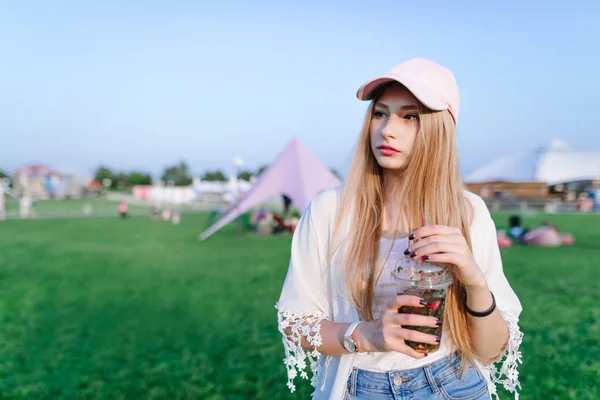 Menina bonita e elegante bebe uma refrescante limonada semi-finamente sumida andando pelo parque . — Fotografia de Stock