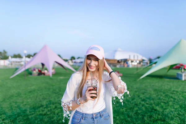 Retrato de uma bela jovem mulher sorrindo e olhando para a câmera enquanto caminha em um parque de férias moderno . — Fotografia de Stock