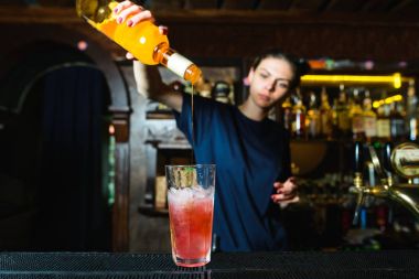 Kız barmen gece kulübünde lezzetli bir alkollü kokteyl oluşturur. Barmen şurubu bir alkollü kokteyl dökülen..
