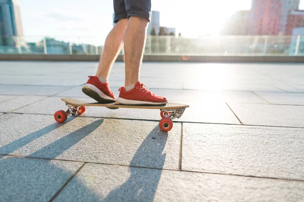 En man skater rider en skateboard på bakgrund av solen. Gatan koncept. På bakgrund av staden. — Stockfoto