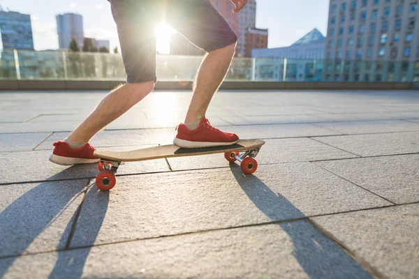 빨간 운동 화에 젊은 남자 보더 longboard에 타고 있는 동안 지상에서 그의 다리에 달려있다. 거리 개념. — 스톡 사진