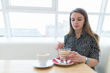 Güzel bir kadın, modern ve şık bir restoranda lezzetli bir tatlı yiyor. Kadın üzerinde odaklanmak.