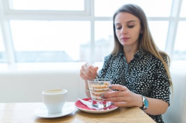 Tatlı üzerinde odaklanın. Güzel bir kadın bir iştah açıcı, güzel tatlı bir modern ve hafif kafede yiyor..