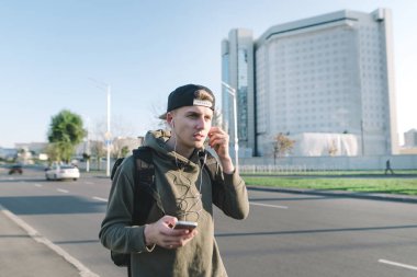 Güzel, genç bir öğrenci ile şehir etrafında geziniyor ve müzik kulaklık road yakınındaki bir sırt çantası. Yaşam tarzı ve insanlar kavramı.