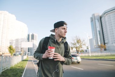 Onun şehir'in elinde kahve ile sokakta yürürken ve müzik kulaklık şık genç bir adam portresi. Yaşam tarzı kavramı.
