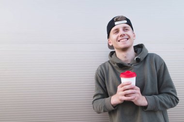 Bir kap hafif bir arka plan üzerinde olumlu bir gülümseyen öğrenci portresi ile onun elinde sıcak içecek bir fincan.