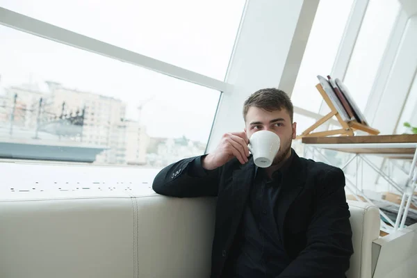 Przystojny bizneswoman, siedząc w kawiarni przy oknie i picia kawy. Przerwa na kawę w stylowej kawiarni nowoczesne — Zdjęcie stockowe