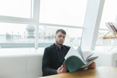 Bir sakallı bir işadamı vikan yakınındaki güzel bir restoranda masada oturur ve bir dergi okur. Öğle yemeği molası okuyarak