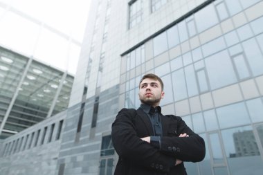 Modern mimari zemin karşı takım elbiseli sakallı ciddi bir genç adam portresi. Başka tarafa bak. İş portre. İş kavramı