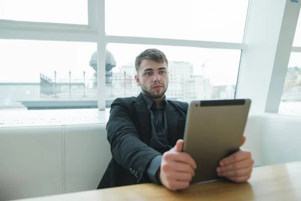 Diák ül egy kávézóban, és használ a internet tabletta. Egy éber szem alatt a kávészünet minialkalmazásban. — Stock Fotó