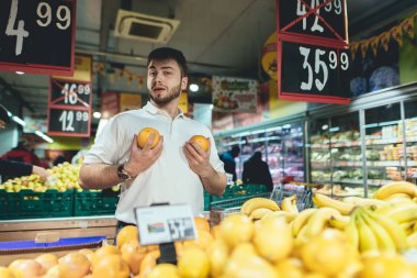 Komik bir genç adam süpermarket maymunlar tarafından oynanır ve kameraya benziyor. Meyve mağazasında satın. Süpermarkette alışveriş.