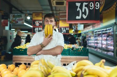 Muz onun elinde olan bir adam bir süpermarkette alışveriş yaparken teşkil etmektedir. Alıcı depodaki meyve satın alır. Bir süpermarkette alışveriş