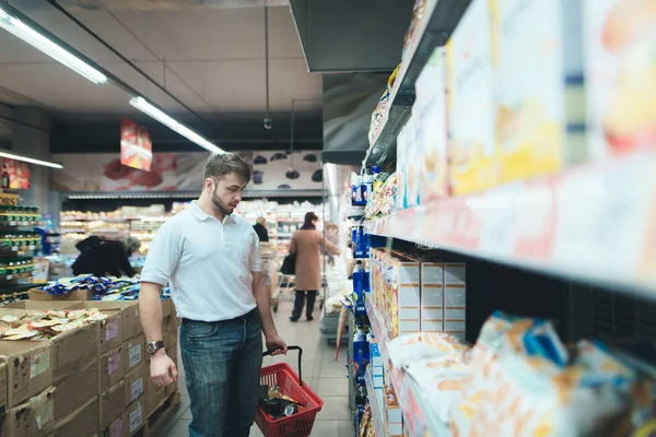 A family man chooses food at a supermarket. A man buys products in the store. — Stock Photo, Image