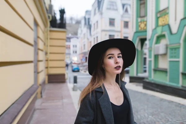 Ulice portrét stylové ženy na pozadí ulice staré krásné město. Krásná dívka v klobouku stojí na pozadí barevných staré architekt — Stock fotografie