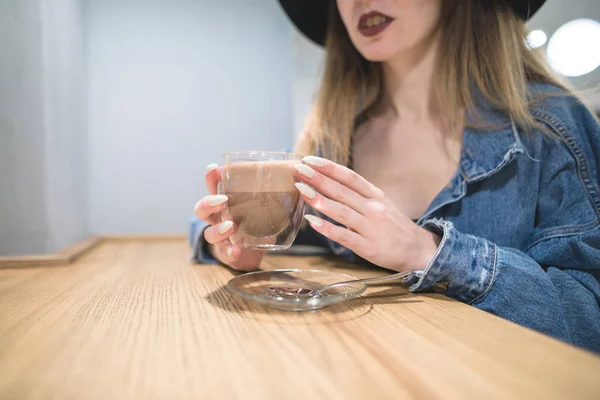 Uma chávena de café na mão de uma mulher com uma bela manicura. A menina hipsters segura uma xícara de bebida quente. Concentre-se no copo . — Fotografia de Stock