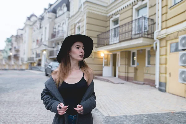 Abendporträt einer stilvollen Frau vor dem Hintergrund der schönen Architektur der Altstadt. das Mädchen posiert vor der Kamera auf dem Hintergrund des alten architektonischen Vorhangs. — Stockfoto