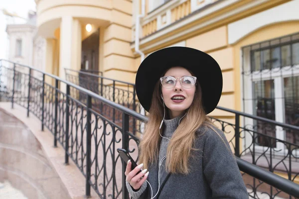 Porträt eines stilvollen Mädchens mit Hut und Brille vor dem Hintergrund alter Architektur. glückliches Mädchen mit Zahnspange lächelt aufrichtig. — Stockfoto