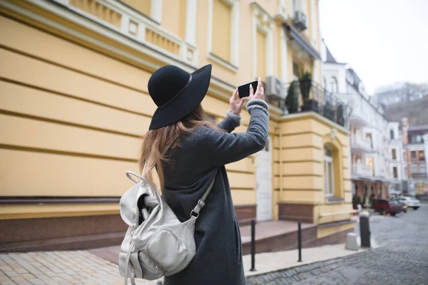 Стильна туристична дівчина фотографує старе місто на власному смартфоні. Жінка фотографує архітектуру на телефоні . — стокове фото