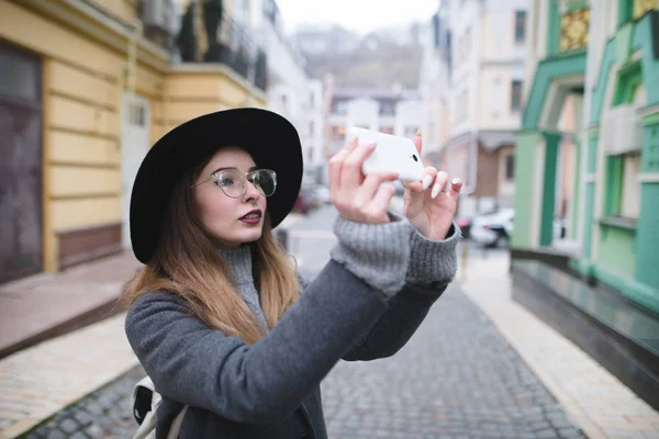 Belle fille élégante photographiant une photo de rue au téléphone. Une touriste fait une photo d'architecture sur un smartphone . — Photo