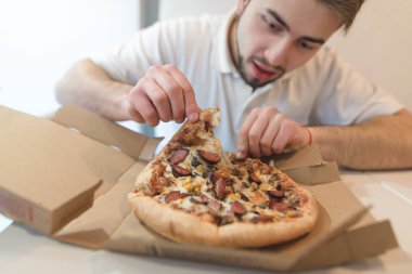 Bir sakallı bir adam bir karton kutu lezzetli bir parça pizza alır ve ona bir iştahla bakar. Pizza üzerinde odaklanın. Pizzacı leziz Öğle Yemeği.