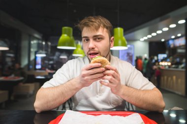 Bir fast-food Restoran hamburger ile bir sakallı bir adam oturuyor 