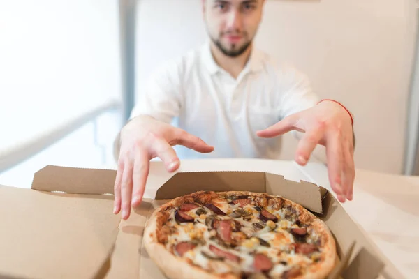 O homem vai tirar um pedaço de pizza fresca e quente da caixa. As mãos do marido sobre um capuz de pizza . — Fotografia de Stock