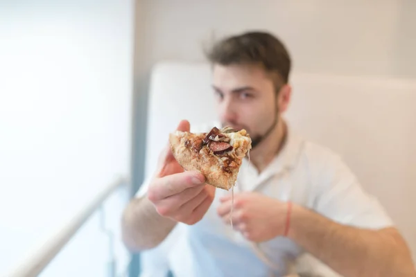 Egy ember tart egy darab pizza keze, és elküldi a kamera. Egy darab pizza a középpontban. — Stock Fotó