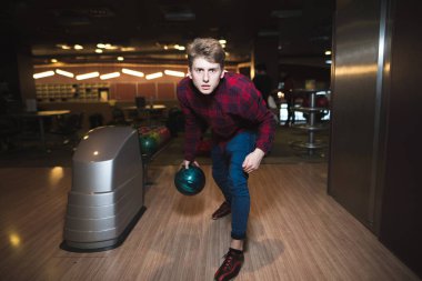 Bowling için mavi bir top bowling oynayan genç adam. Bir adam bir kurşun bir çubuğa atar..