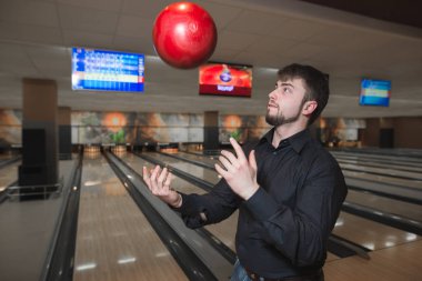 Bir iş adamı sakallı bir bowling topu parça oynarken bir arka plan juggles. Bowling klübünde oynamaktadır.