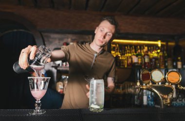 Barmen gece kulübü barda güzel alkollü kokteyller oluşturur. Barmen bir shaker alkol bir cam içine dökülen.
