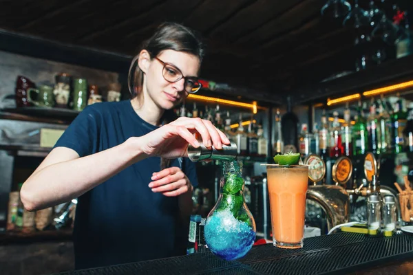 Дівчина-бармен створює красиві яскраві коктейлі в барі. Бармен змішує інгредієнти коктейлю . — стокове фото