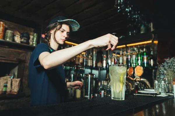 A beautiful bartender girl creates an alcoholic cocktail at the nightclub bar. — Stock Photo, Image