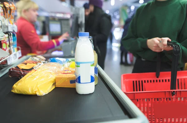 La chica se para en el supermercado y espera una cola. El negocio hace compras en la tienda . — Foto de Stock