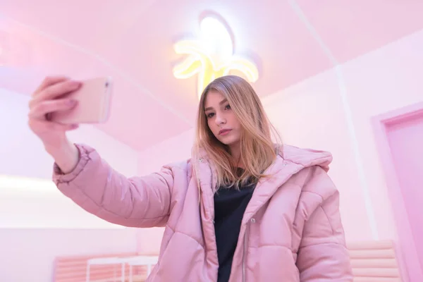 Uma menina bonita em rosa leva um sephi em seu próprio snapphone no fundo interior rosa. Vida rosa — Fotografia de Stock